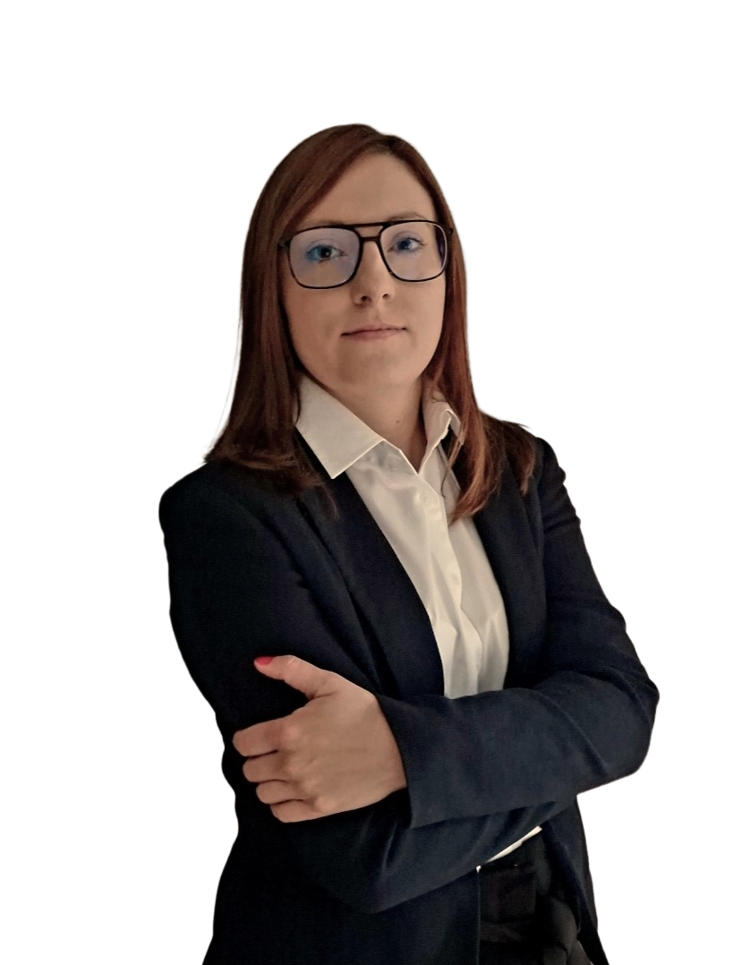 Kobieta w eleganckim, ciemnym garniturze i białej koszuli, stojąca z założonymi rękami na białym tle, pozująca do profesjonalnego zdjęcia biznesowego.